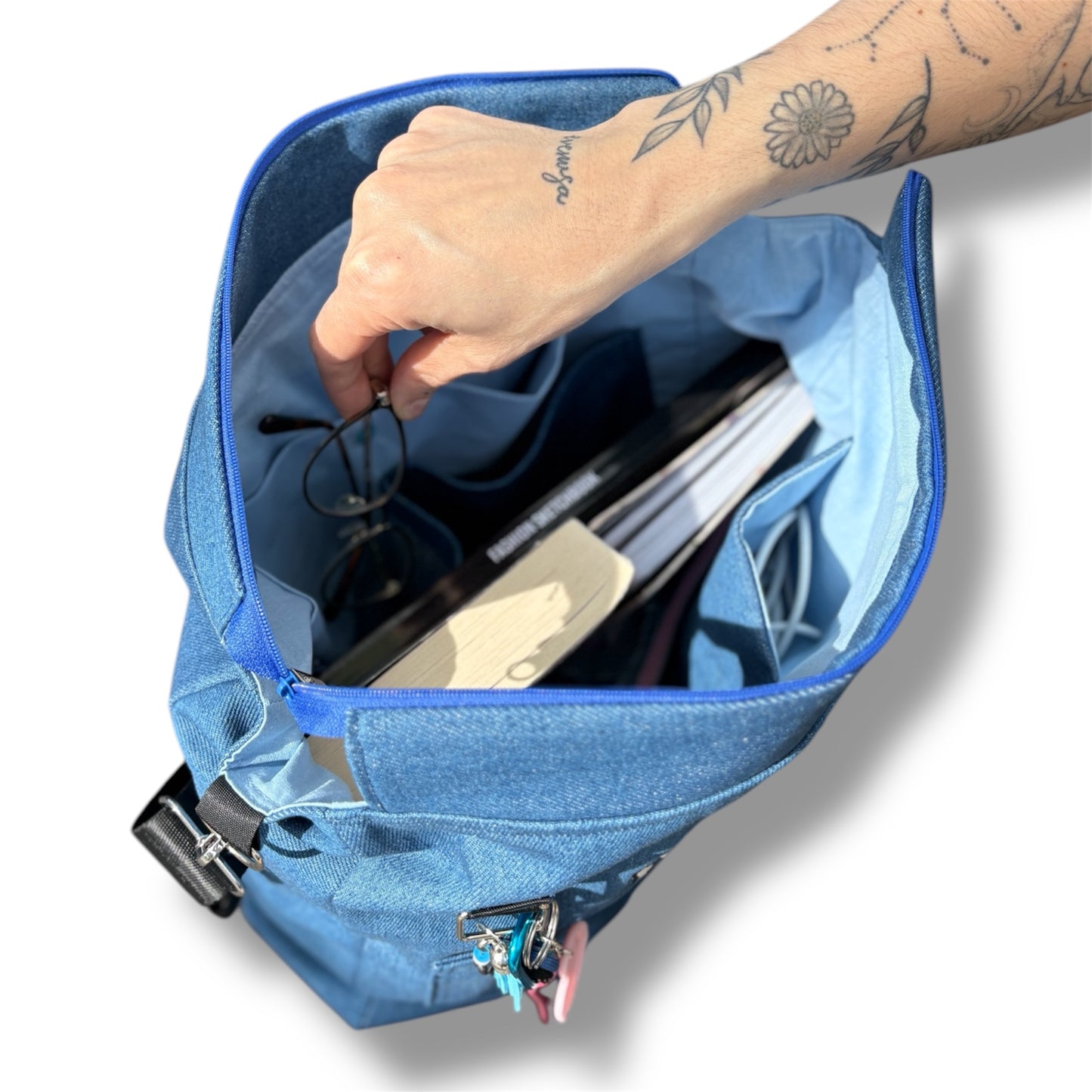 Top-down view inside the Skyline Bag with visible compartments holding glasses, fashion sketchbooks, and a laptop — ideal for everyday use.