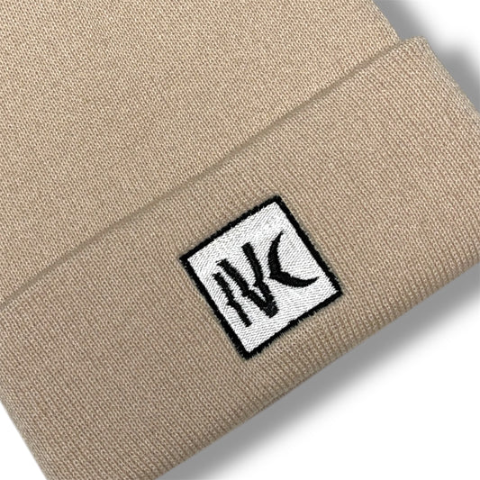 Close-up of IVENUSA beige knit beanie with white embroidered IVC logo patch on the front cuff – minimalist streetwear detail.