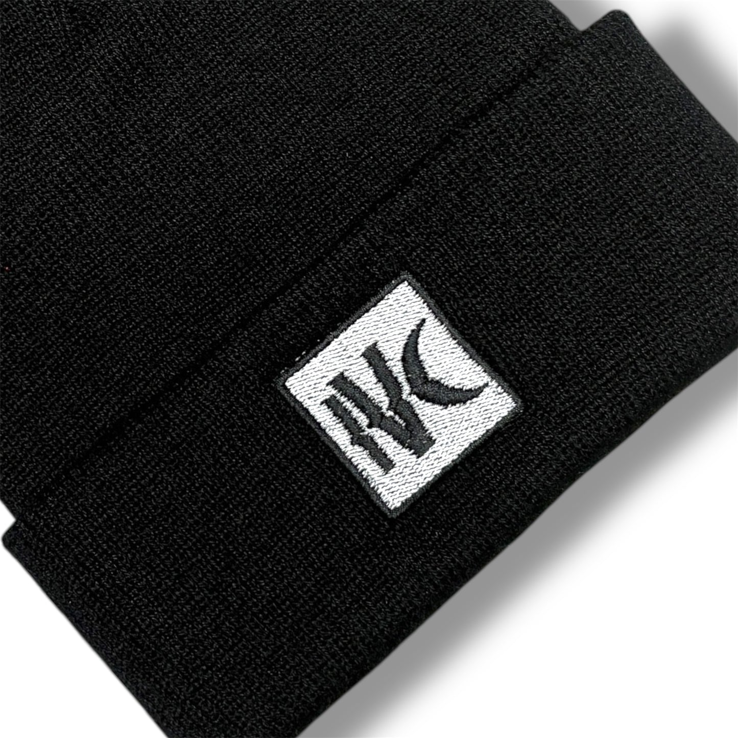 Close-up of IVENUSA black knit beanie featuring minimalist white square IVC logo patch stitched on the cuff.