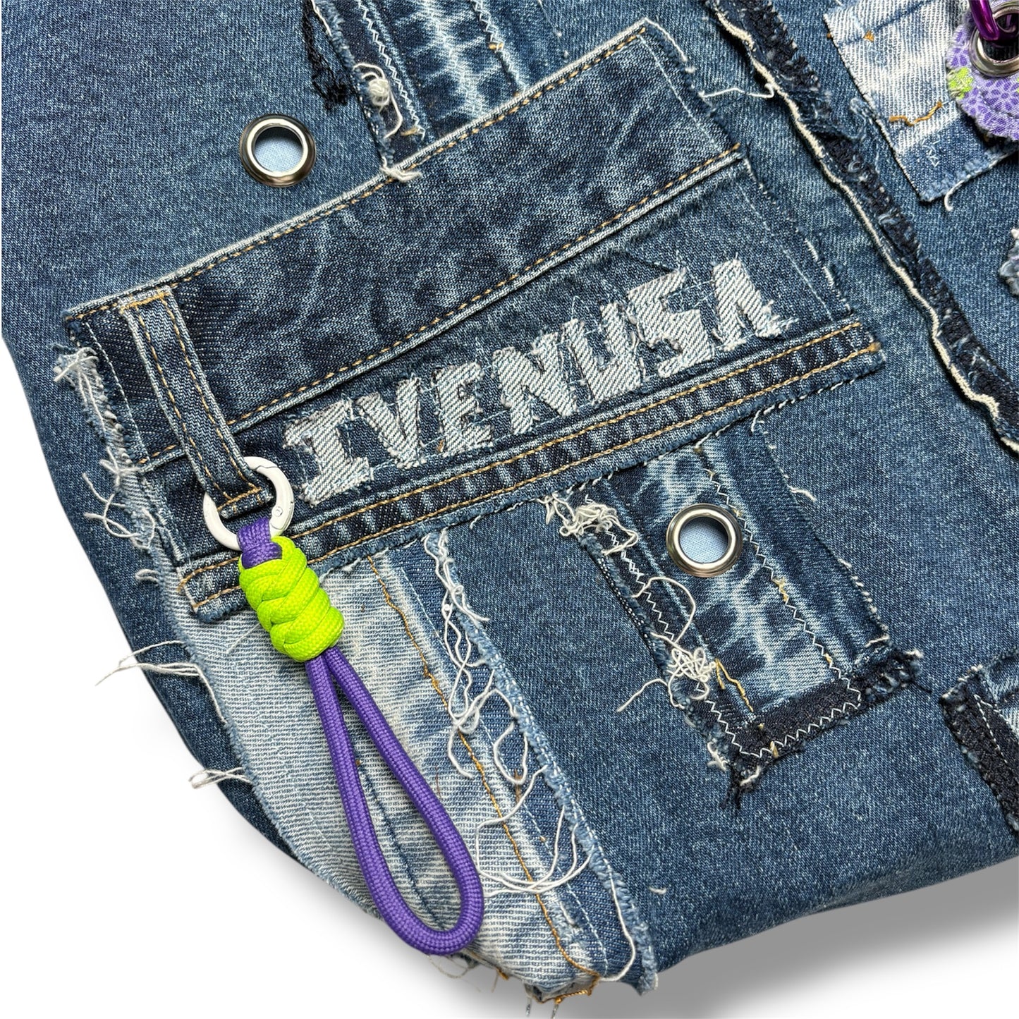 Detail of front utility pocket and IVENUSA embroidered logo on repurposed denim tote bag with neon and purple keychain.