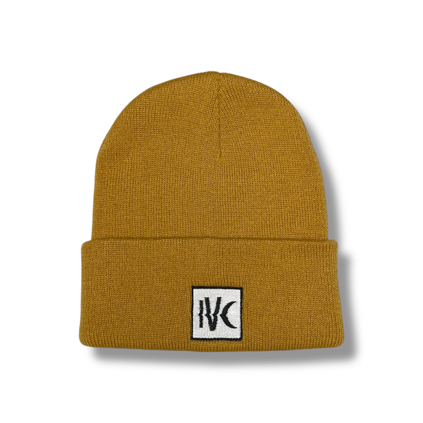 Close-up of IVENUSA mustard knit beanie with black and white IVC logo patch stitched on the folded cuff.