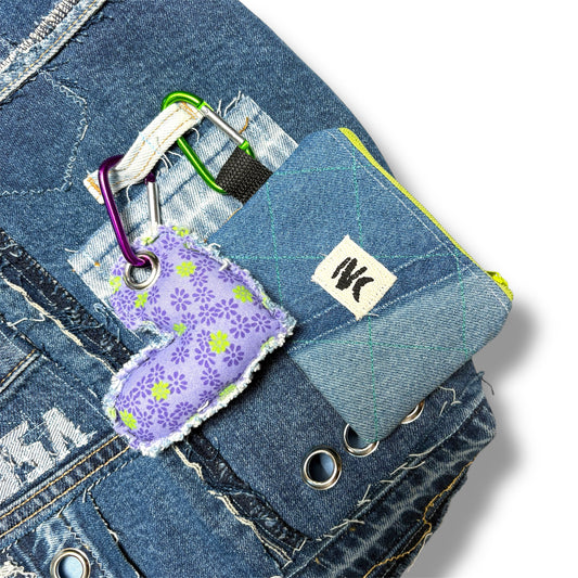 Detail of purple floral heart keychain and mini patchwork denim coin pouch clipped to urban upcycled tote bag.