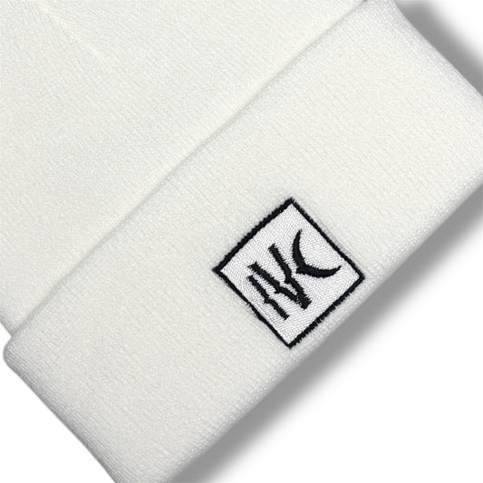 Close-up of IVENUSA white knit beanie showcasing high-contrast IVC embroidered patch stitched on the front cuff.