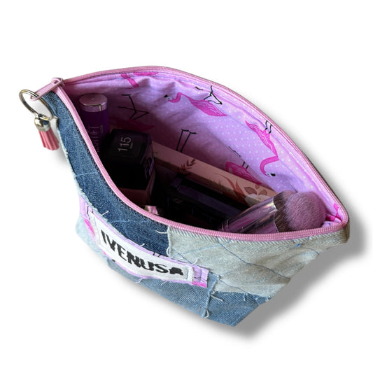 Open patchwork denim makeup bag showing pink flamingos, blush zipper, and stored cosmetics