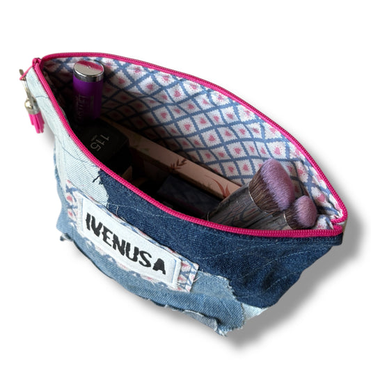 Open patchwork denim makeup bag showing blue and pink striped lining, zipper, and stored cosmetics
