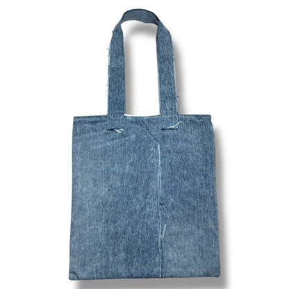 Rear view of the Cada Vez Que Me Miras tote bag with a clean, two-tone denim panel design and reinforced stitched handles.