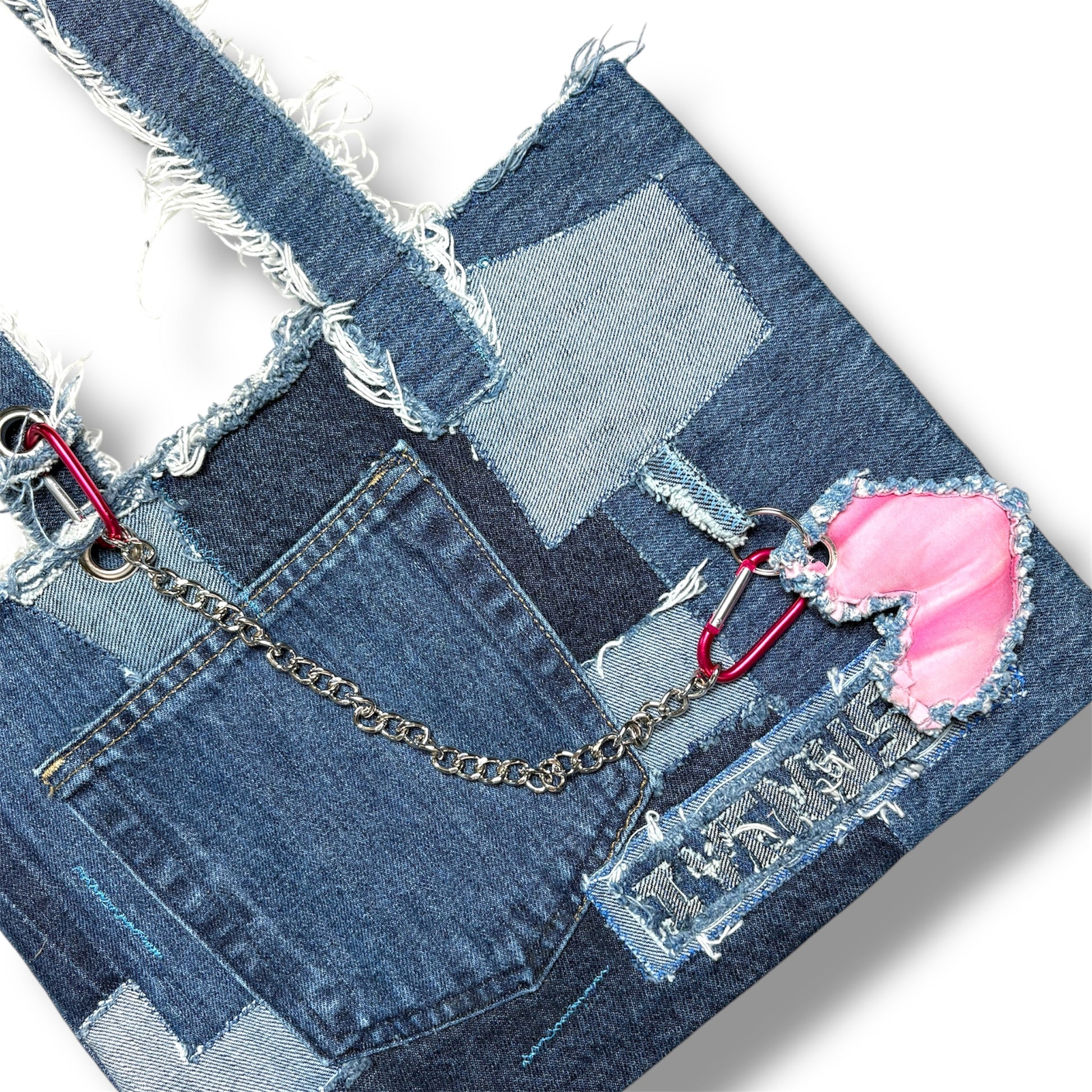 Close-up shot of the Denim Pink Handbag showing patch stitching, frayed textures, and pink heart keychain with silver chain.