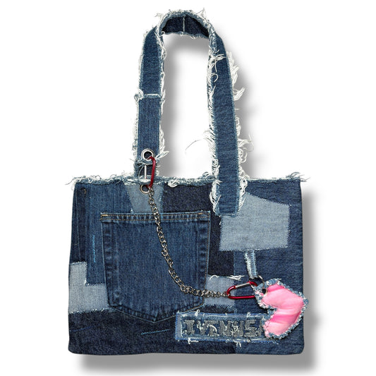 Front view of the Denim Pink Handbag featuring patchwork denim, a frayed strap design, and a pink heart keychain accent.