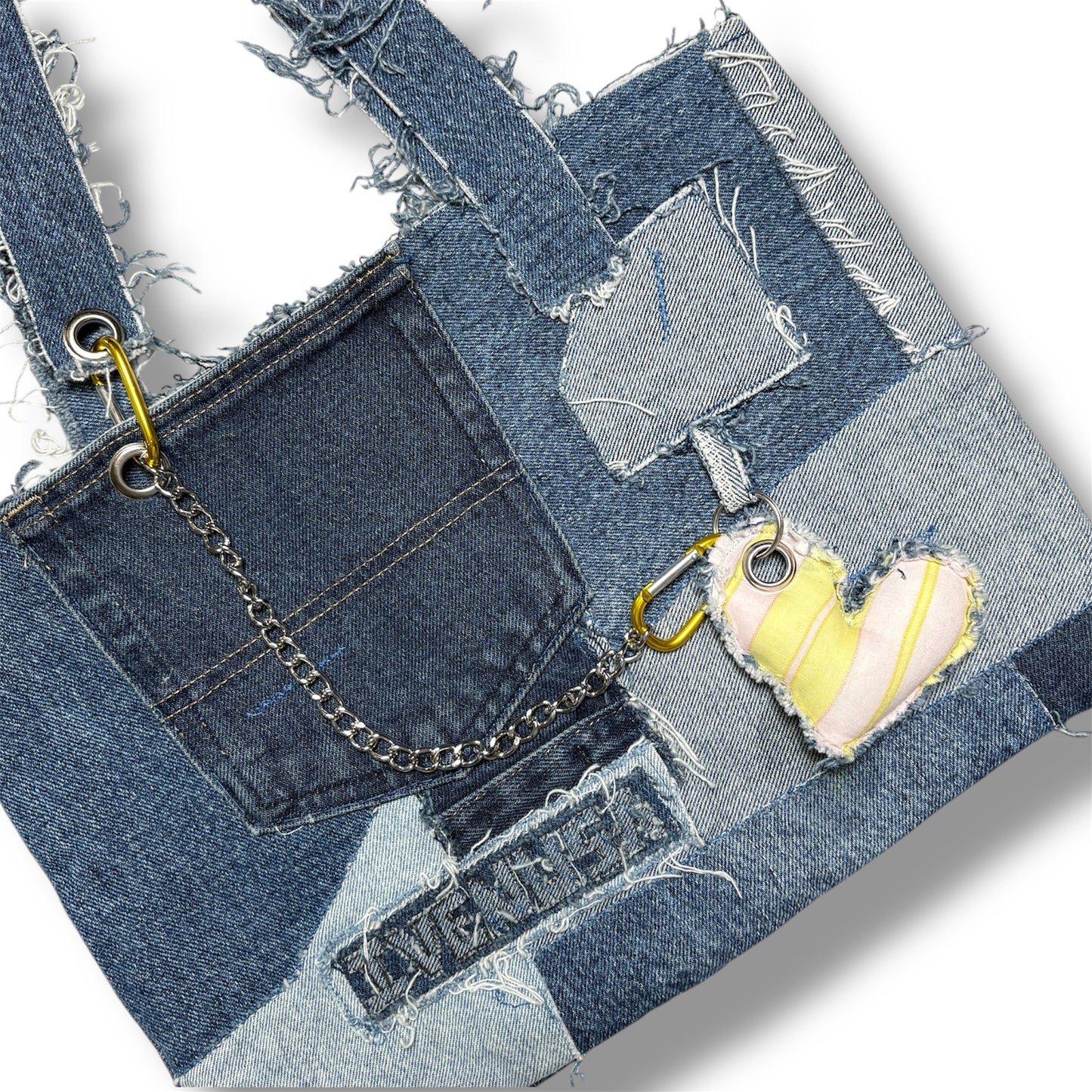 Close-up of Denim Yellow Handbag showing the front pocket stitching, patchwork texture, and yellow heart-shaped charm on gold carabiner