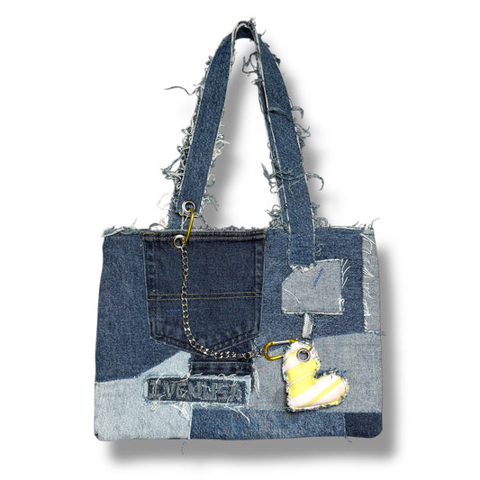 Front view of the Denim Yellow Handbag featuring patchwork denim, frayed handles, a front pocket, and a yellow heart charm