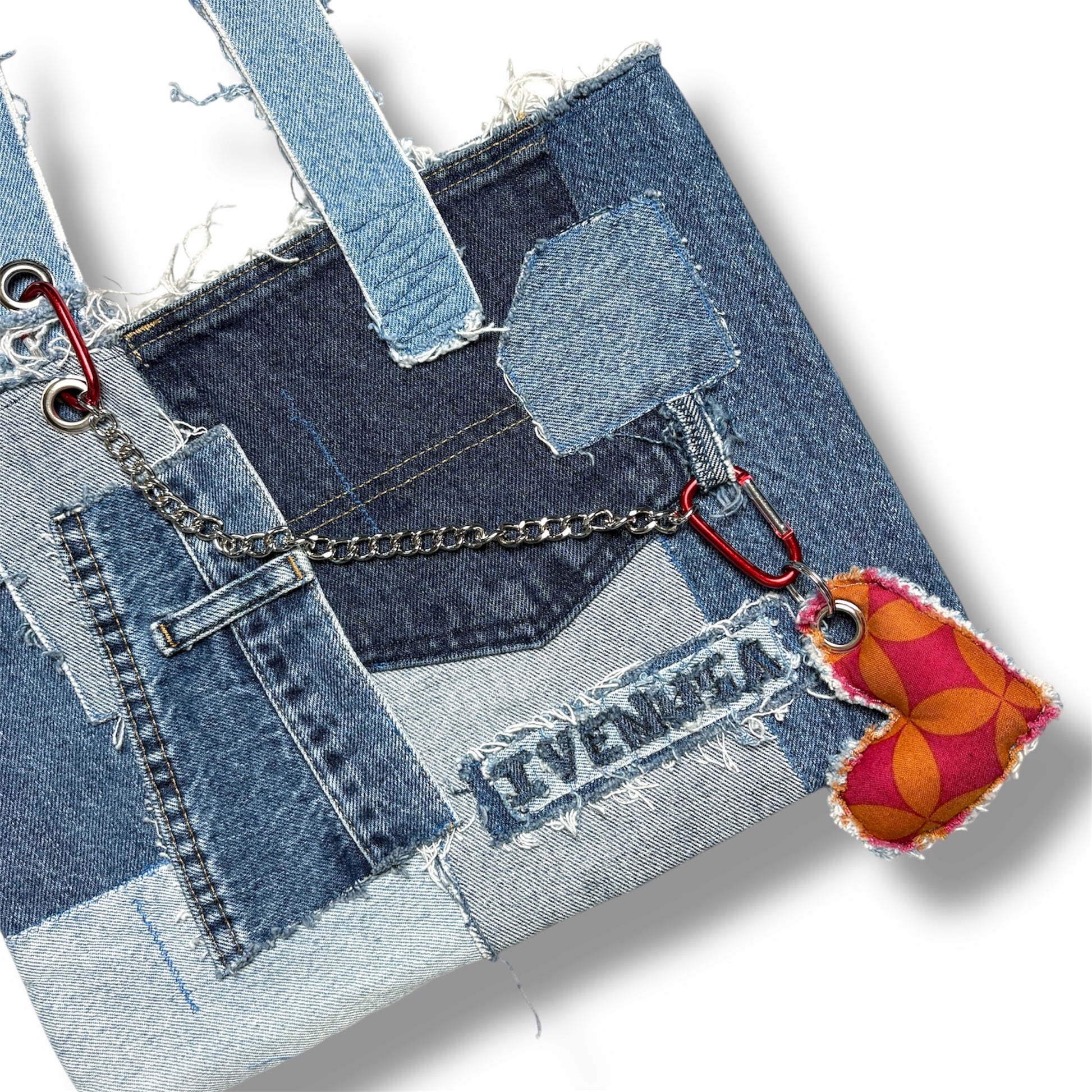 Close-up of the Denim Red Handbag showcasing red heart keychain and patchwork pocket detail with chain accent.