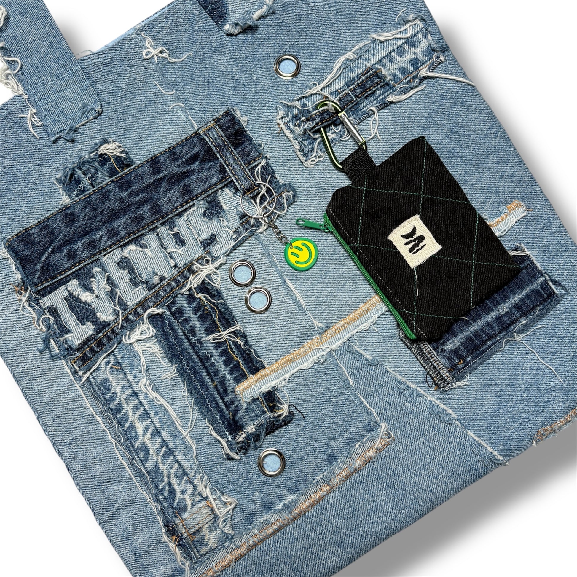 Close-up of the Iconic Green denim tote showing IVENUSA patch, chain ring, and stitched wallet pouch on patchwork surface.