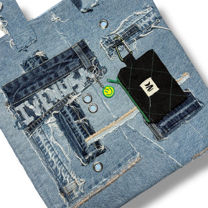Close-up of the Iconic Green denim tote showing IVENUSA patch, chain ring, and stitched wallet pouch on patchwork surface.