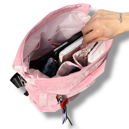 Top-down view of IVENUSA Rosé Avenue Bag showing pink lining and compartments filled with a fashion sketchbook, planner, glasses, and other daily items.