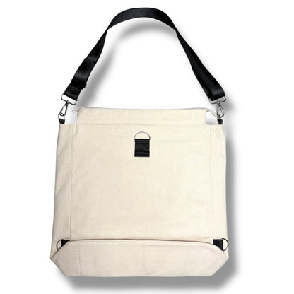 Back of the Rush Hour Bag by IVENUSA featuring clean beige canvas, sturdy structure, and detachable black shoulder strap with D-ring hardware.
