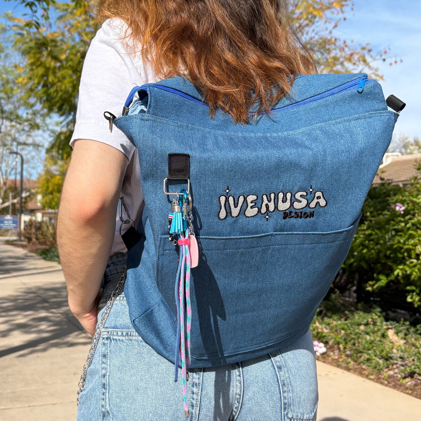 Model wearing the IVENUSA Skyline Bag on their back as a backpack, styled with casual jeans in an urban outdoor setting.