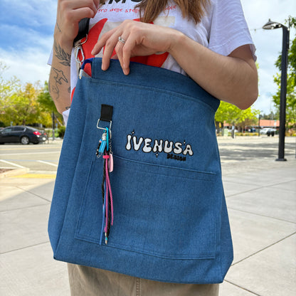 Model carrying the Skyline Bag across one shoulder, showcasing the IVENUSA logo and colorful keychain in a laid-back city streetwear vibe.