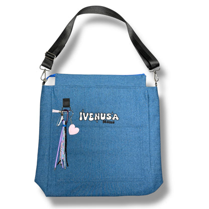 IVENUSA Skyline Bag in blue with front pocket, embroidered logo, and detachable pastel keychains including a pink heart and multicolor tassels.