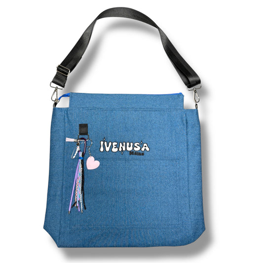 IVENUSA Skyline Bag in blue with front pocket, embroidered logo, and detachable pastel keychains including a pink heart and multicolor tassels.