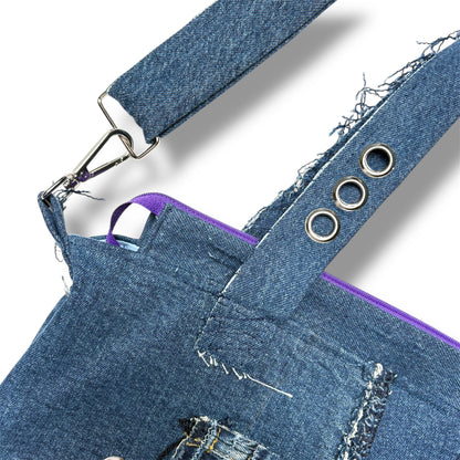 Close-up of adjustable denim strap with silver grommets and purple zipper lining on handcrafted tote bag.