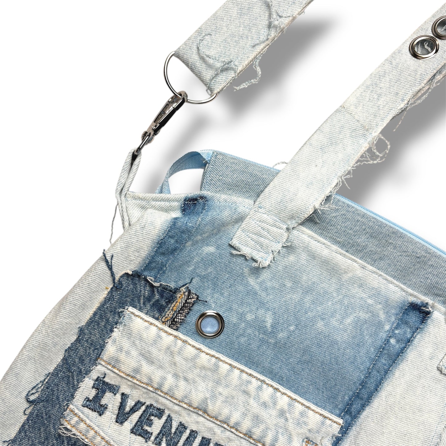 Close-up of detachable denim strap with grommet hardware and reinforced stitching on IVENUSA light-wash tote.