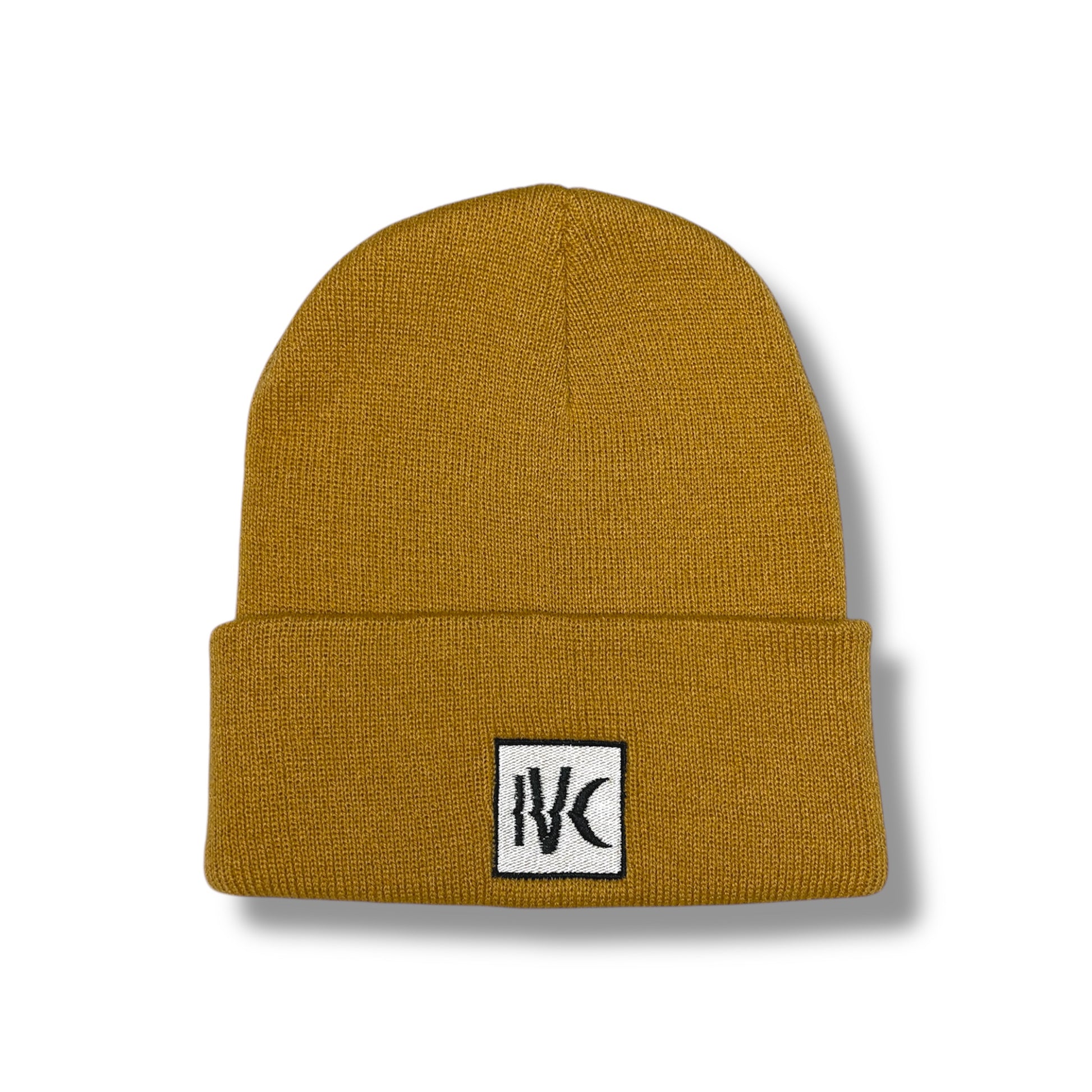 Close-up of IVENUSA mustard knit beanie with black and white IVC logo patch stitched on the folded cuff.