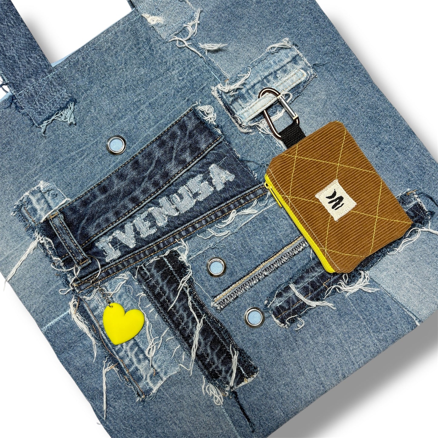 Zoomed-in detail of the Iconic Yellow tote's front pocket, chain, yellow heart charm, and pouch attached to the handle.