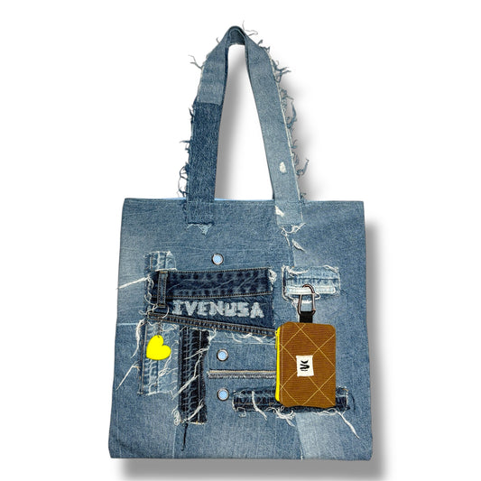 Close-up front view of the Iconic Yellow tote bag made of patchwork denim, featuring a yellow heart charm and brown mini pouch.