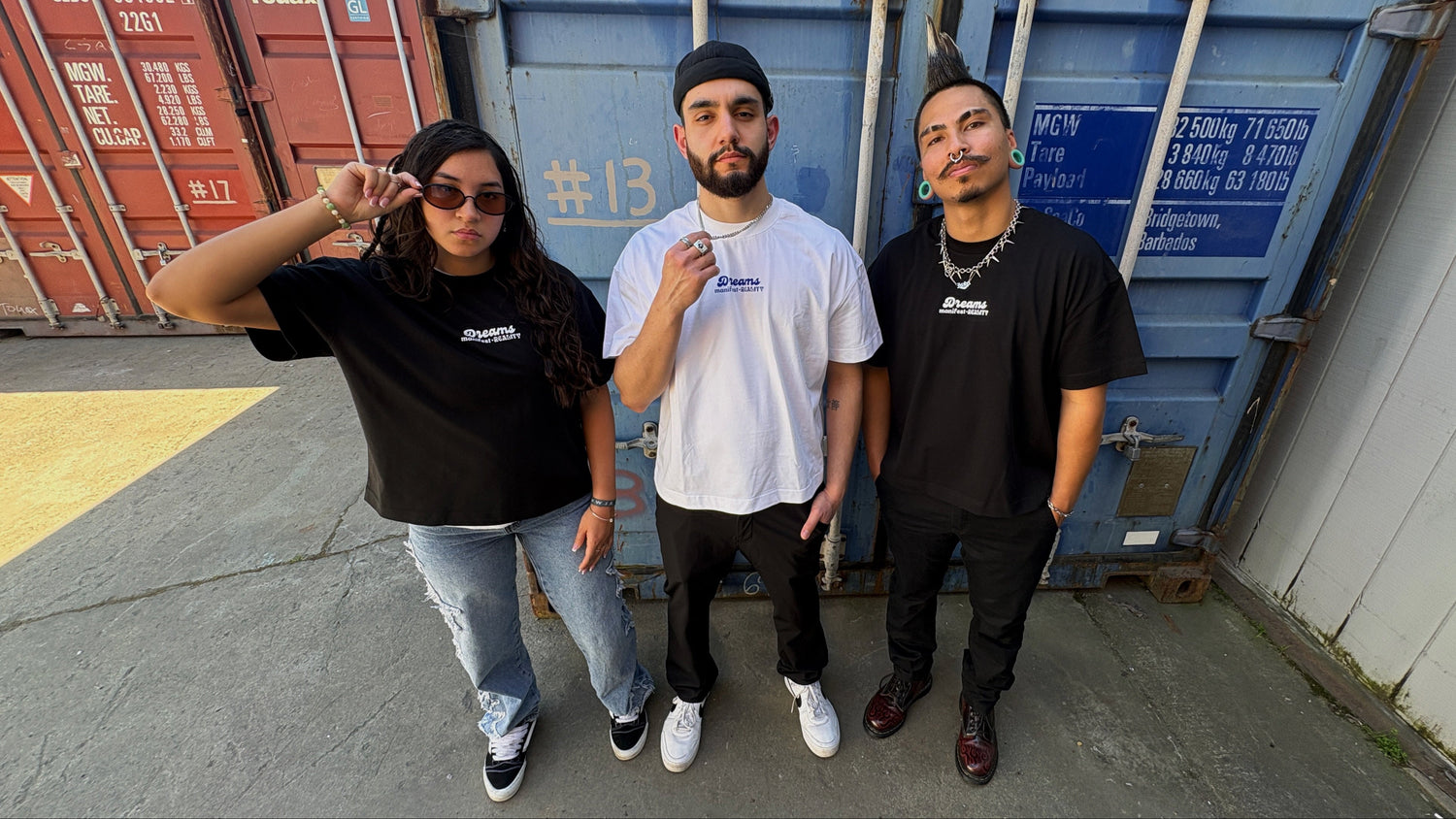 Three models wearing Ivenusa Design DMR oversized t-shirts posing in front of shipping containers