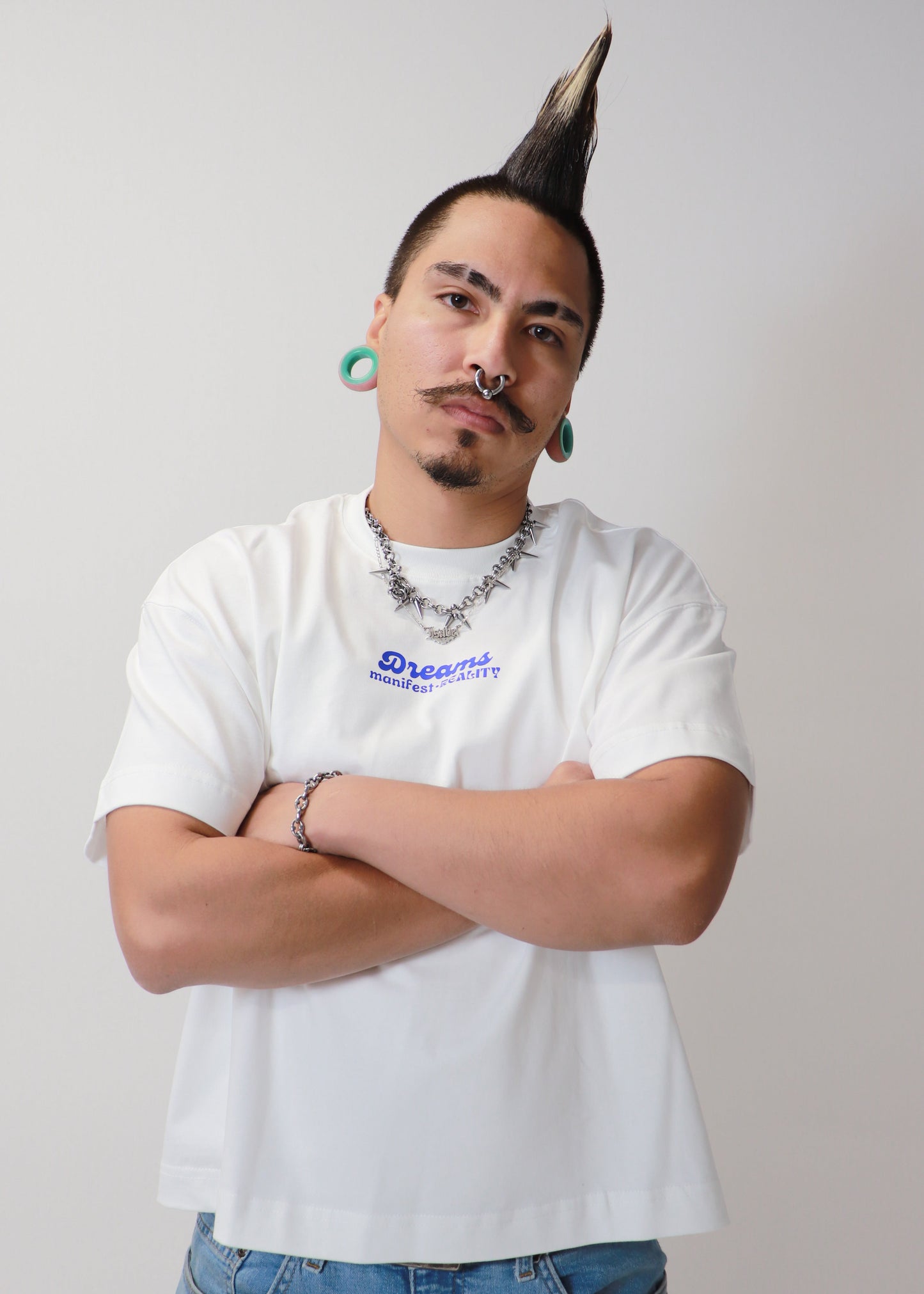 Male model posing with arms crossed wearing white DMR oversized tee