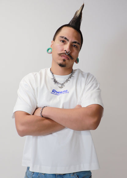Male model posing with arms crossed wearing white DMR oversized tee